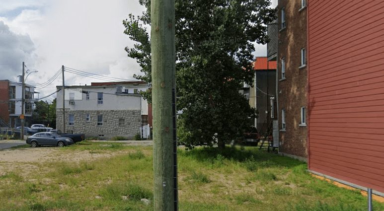 Vacant grassy urban lot between two apartment buildings in Trois-Rivières